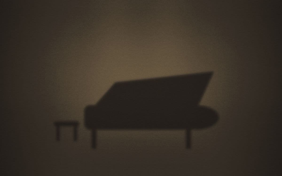 A grand piano lit on a darkened concert stage.