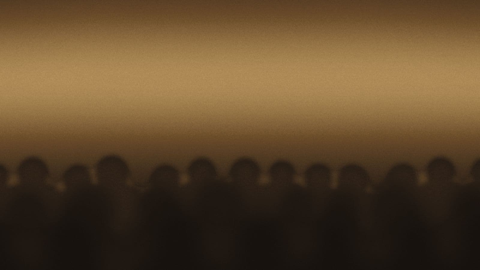 An audience in darkness, lit only by the stage in front of them.