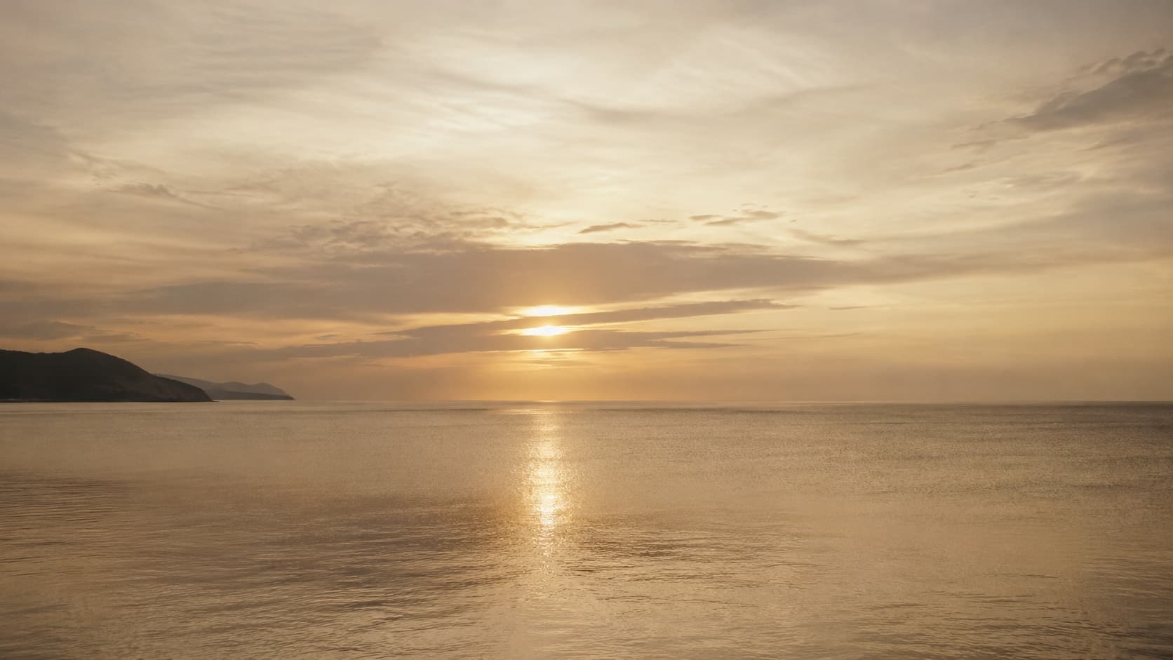 A wide dusk horizon with light broken across the water.