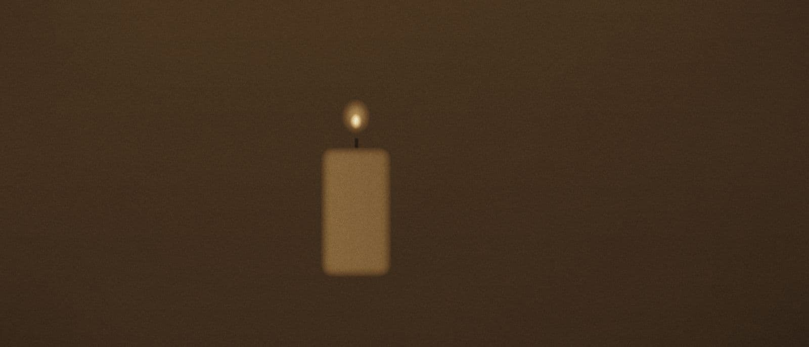 A single candle burning on a dark table.